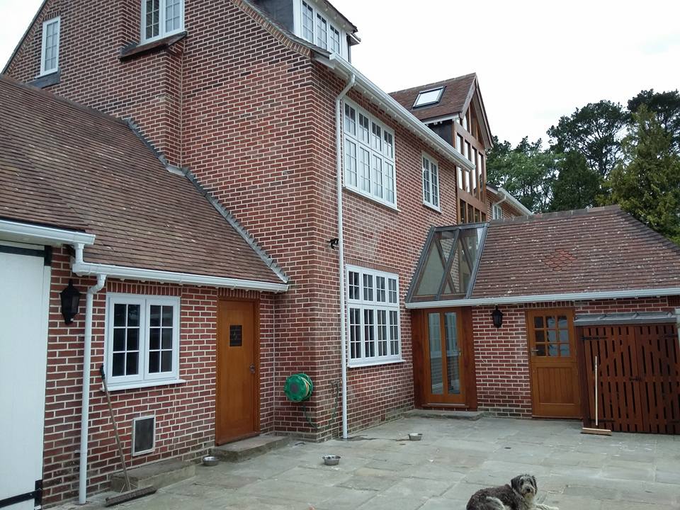The rear courtyard of a large red brick house with oak doors and tile-hung roofs