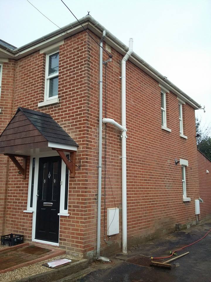The side elevation of a modern red brick house with fresh, even pointing and a tiled door canopy