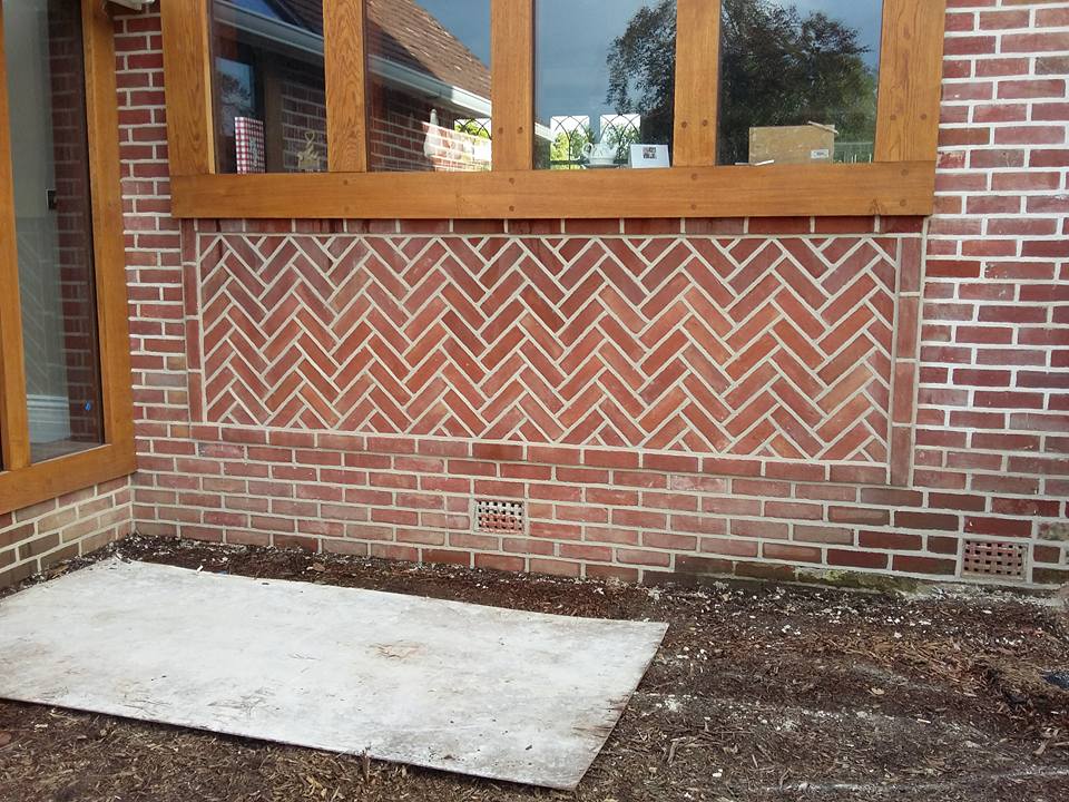 A herringbone brick infill panel set beneath an oak-framed window, with a soldier course border